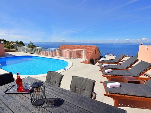 taras ze stołem i krzesłami oraz basenem w obiekcie Holiday Home Damjanović by Interhome w mieście Prigradica