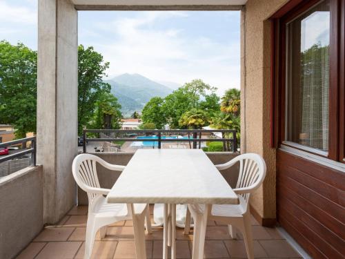 a white table and chairs on a balcony with a view at Apartment Resort al Centro-1 by Interhome in Massagno