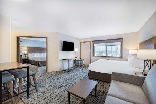 ダルースにあるAmericInn by Wyndham Duluth South Proctor Black Woods Event Ctrのベッドとリビングルームが備わるホテルルームです。