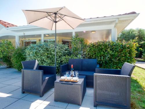 a patio with two chairs and a table with an umbrella at Holiday Home Eden Parc by Interhome in Lacanau-Océan