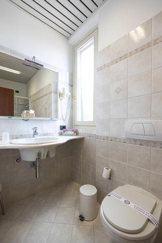 a bathroom with a toilet and a sink and a mirror at Hotel Il Portico by LVG Hotel Collection in Cannobio