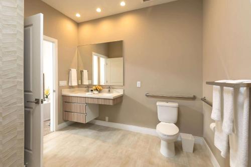 a bathroom with a toilet and a sink and a mirror at Magic Village Views Trademark Collection by Wyndham in Orlando
