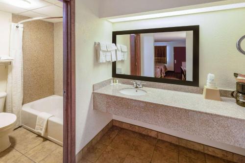 a bathroom with a sink and a toilet and a mirror at Super 8 by Wyndham Seguin in Seguin