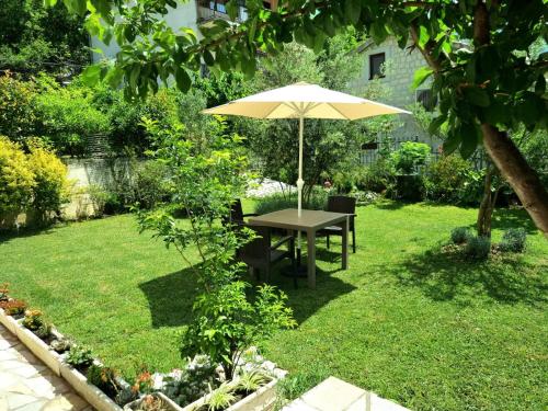 a table with an umbrella in a garden at Apartments Krstos place in Kotor