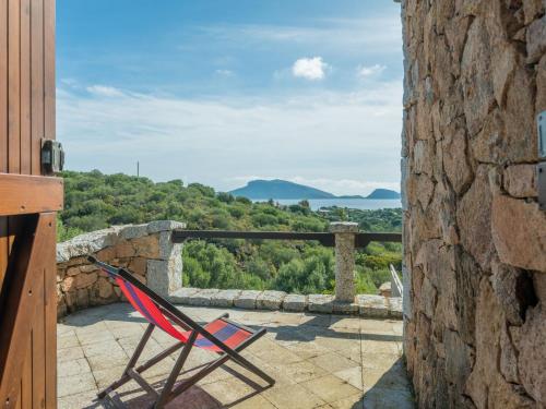 a red chair sitting on a stone balcony with a view at Holiday Home Pietra by Interhome in Pittulongu