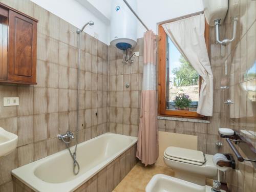 a bathroom with a tub and a toilet and a sink at Holiday Home Pietra by Interhome in Pittulongu
