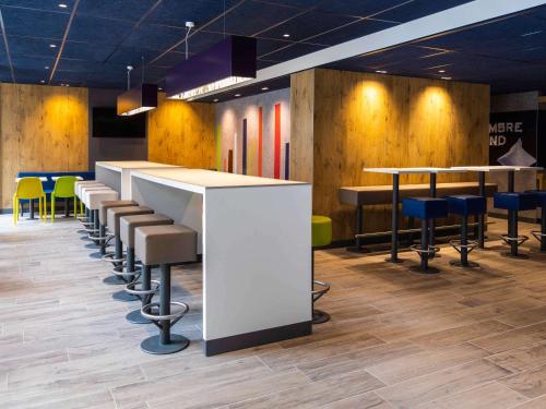 a bar with stools and tables in a room at ibis budget Strasbourg Centre Republique in Strasbourg