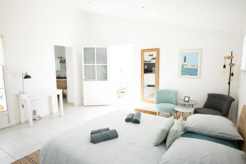 a white bedroom with a bed and a chair at Maison 3 chambres plus 1 studio indépendant in Sainte-Marie-de-Ré