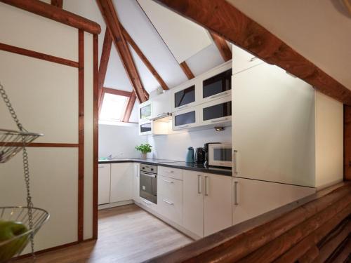 uma cozinha com armários brancos e piso em madeira em Holiday Home Am Sternberg 4 by Interhome em Frankenau