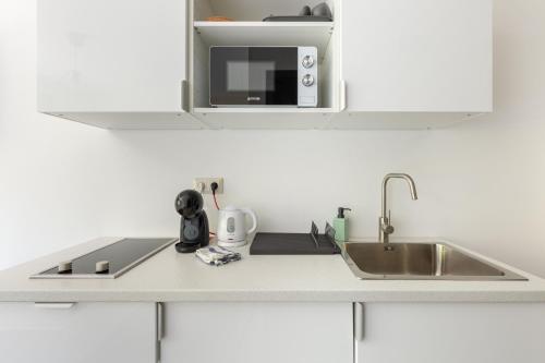 a kitchen counter with a sink and a microwave at Pauzo Balaton in Balatonföldvár