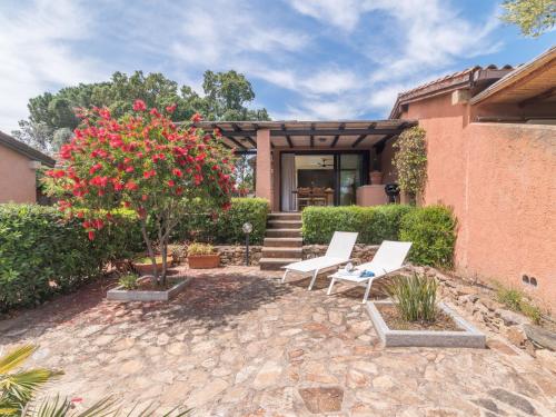 un patio con 2 sillas y un árbol con flores rojas en Holiday Home Dalila by Interhome, en Porto Istana