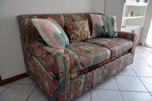 um sofá com almofadas na sala de estar em Appartamento Climatizzato con Piscina Ca' Aurelia em Lido di Savio