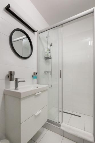 a white bathroom with a shower and a sink at Pauzo Balaton in Balatonföldvár