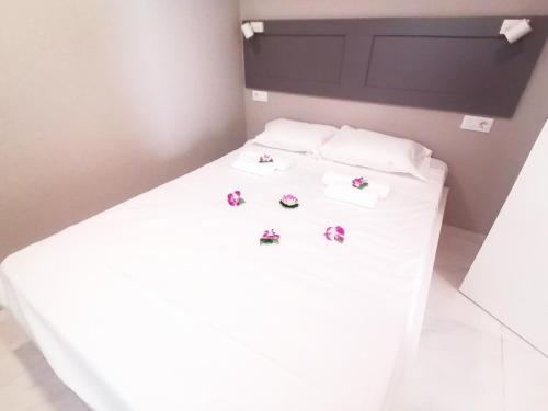a white bed with three pillows and flowers on it at New apartment Alcala 1 room & FREE WIFI in Alcalá