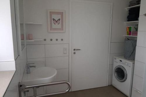 ein Badezimmer mit einem Waschbecken und einer Waschmaschine in der Unterkunft Ferienhaus Bendestorf vor den Toren Hamburgs in Bendestorf