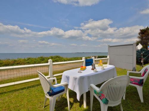 a white table and chairs on a balcony with the ocean at Holiday Home Charme de la plage du Moulin by Interhome in Mesquer