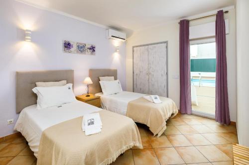 two beds in a room with a window at Villa Nobre by The Portuguese Butler in Albufeira