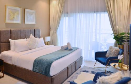 um quarto com uma cama grande e uma cadeira azul em Elegant Studio in park View JVC em Dubai