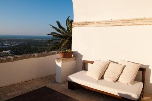 a white couch sitting on a balcony with a palm tree at La Sommità Relais & Chateaux in Ostuni