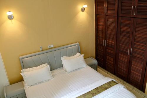a bedroom with a bed with two pillows on it at Residence Le Carat Bonapriso in Douala
