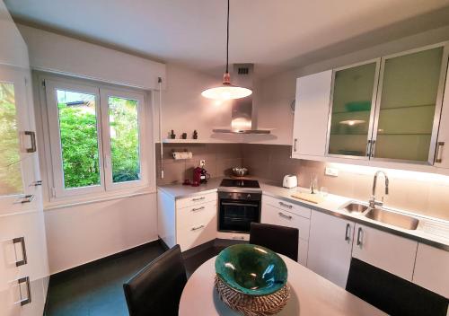 eine Küche mit weißen Schränken und einem Tisch mit einer grünen Schüssel darauf in der Unterkunft Suite Apartment with a view and free parking in Lugano