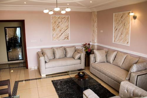 a living room with two couches and a table at Residence Le Carat Bonapriso in Douala