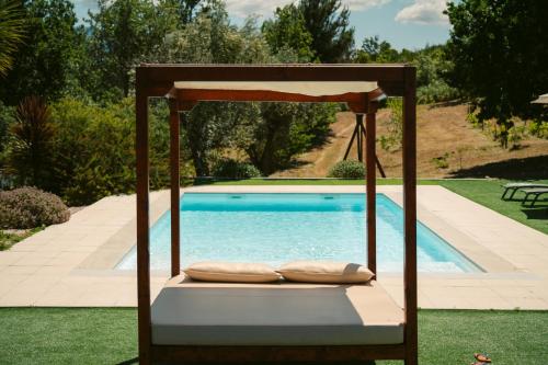 uma cama de baloiço com almofadas ao lado de uma piscina em Pura - Home in Nature em Oliveira do Hospital