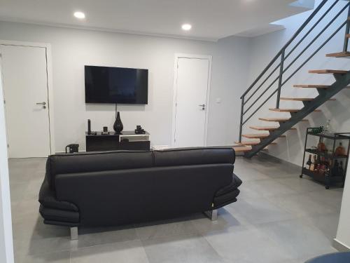 a living room with a black couch and a staircase at Aroeira House in Aroeira