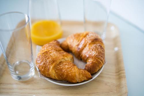 two croissants on a plate on a table with a glass at FRENNESIA Amalfi Coast in Atrani