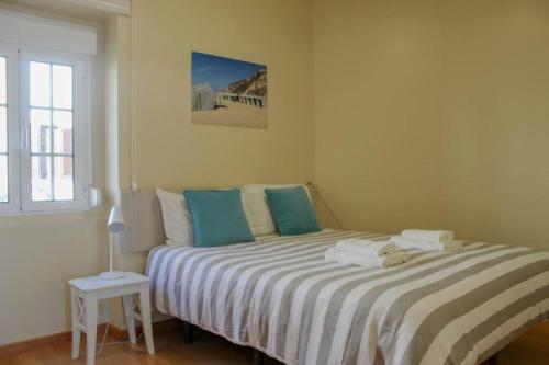 um quarto com uma cama com lençóis azuis e brancos em Casa da Areia na Nazaré