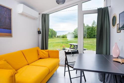 ein Wohnzimmer mit einem gelben Sofa und einem Tisch in der Unterkunft Pilwa 17 - Domek in Pilwa