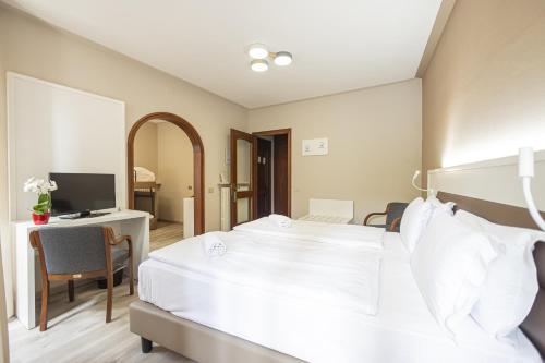 a bedroom with a bed and a desk with a television at Hotel Il Portico by LVG Hotel Collection in Cannobio