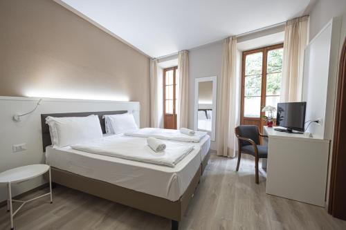 Dormitorio con cama, escritorio y TV en Hotel Il Portico, en Cannobio