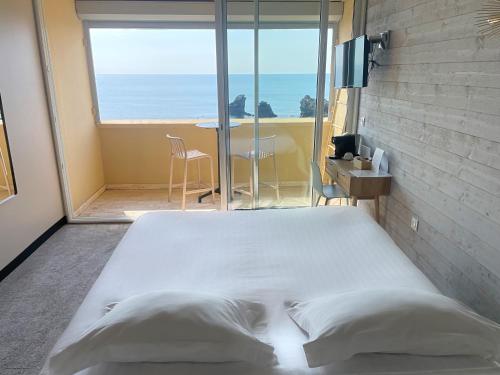 a bed in a room with a view of the ocean at Hôtel La Grande Conque in Cap d'Agde