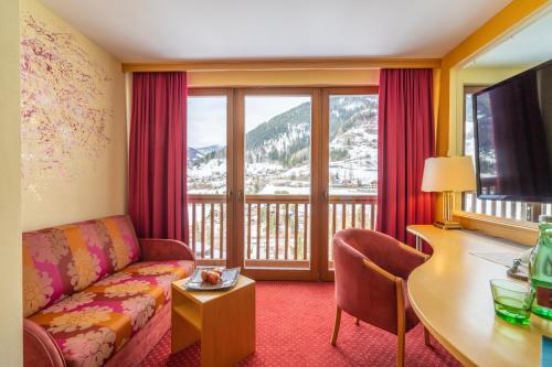 a living room with a couch and a table and a balcony at Der Kirchheimerhof - Superior in Bad Kleinkirchheim