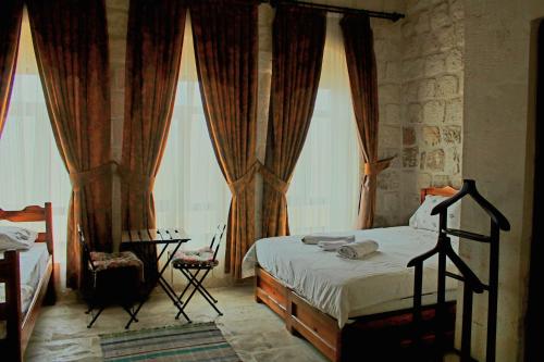 um quarto com uma cama e 2 janelas grandes em Mons Masius Boutique Hotel Cafe em Midyat
