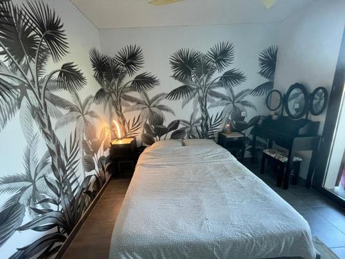 a bedroom with a bed with palm trees on the wall at Villa luxe bord de mer avec piscine et grand jardin in Corbara