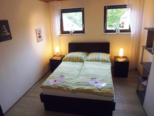 a bedroom with a bed with two windows and two tables at Ferienwohnung am Wald in Unterlüß