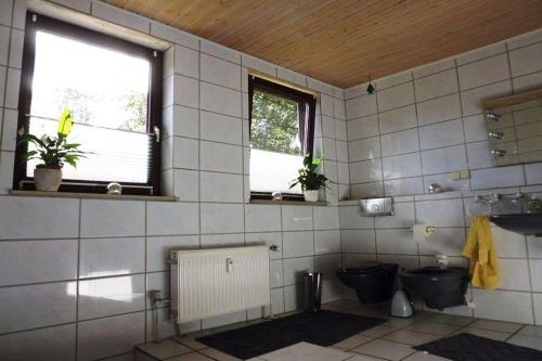 a tiled bathroom with a toilet and a window at Ferienwohnung am Wald in Unterlüß