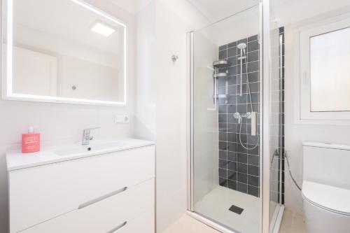 a white bathroom with a shower and a sink at Villa Can Odile By SunVillas Mallorca in Cala de Sant Vicent