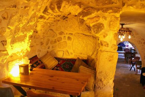Mons Masius Boutique Hotel Cafe في مِديات: غرفة مع طاولة خشبية في جدار حجري