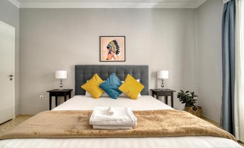 ein Schlafzimmer mit einem großen Bett mit gelben und blauen Kissen in der Unterkunft Alopekis in Athen