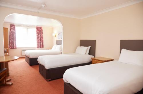 a hotel room with two beds and a table at Farmhouse Innlodge by Greene King Inns in Portsmouth