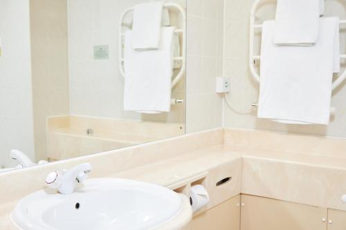 a white bathroom with a sink and a mirror at Farmhouse Innlodge by Greene King Inns in Portsmouth