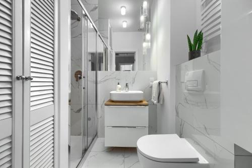 Un baño blanco con inodoro y lavabo. en Apartament Lynx HANZA POOL SAUNA, en Szczecin