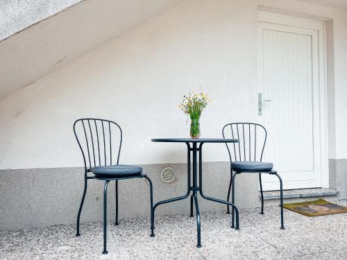 two chairs and a table with a vase of flowers on it at Apartments Mala Korita Soče in Soča