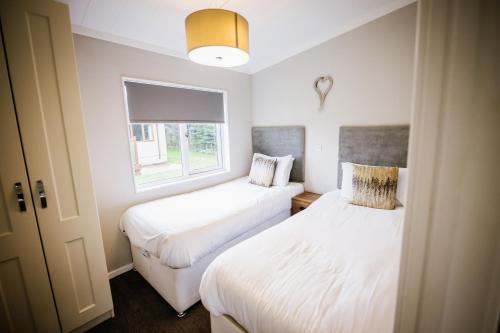2 camas en una habitación pequeña con ventana en Ream Hills Holiday Park en Blackpool