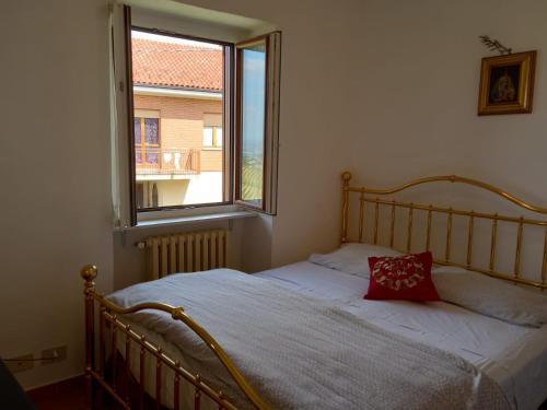 a bedroom with a bed with a red pillow and a window at La casa dei Nonni in Treiso