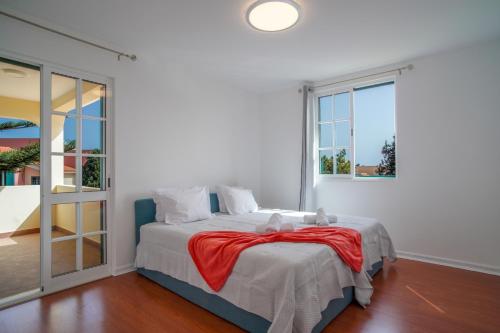 a bedroom with a bed with a red blanket at Jiri Villa With Swimming Pool by MRH in Ponta do Sol