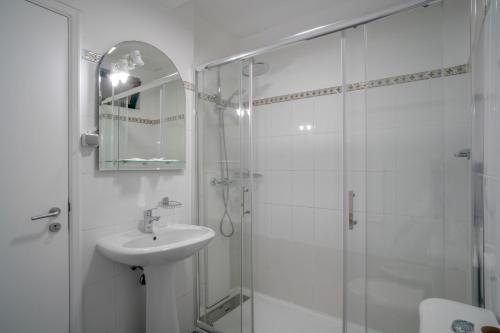 ein weißes Bad mit einem Waschbecken und einer Dusche in der Unterkunft Jiri Villa With Swimming Pool by MRH in Ponta do Sol